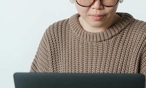 person wearing a knit sweater using a laptop